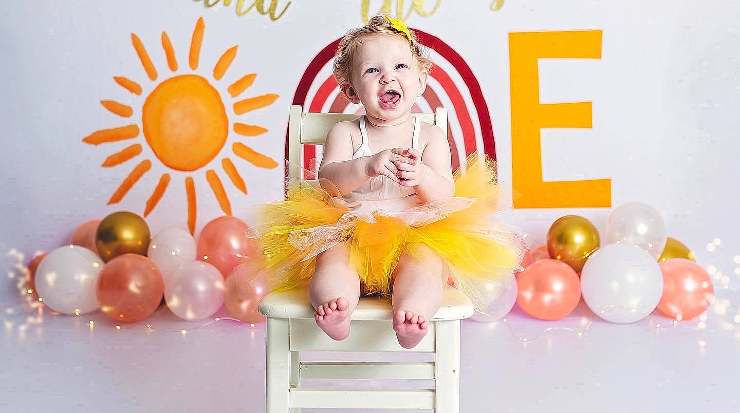 Raya is registered to the contest to win money with this photo: art, baby, baby_toddler_clothing, balloon, child, event, font, fun, happy, magenta, party, party_supply, peach, person, pink, product, room, sitting, smile, sweetness