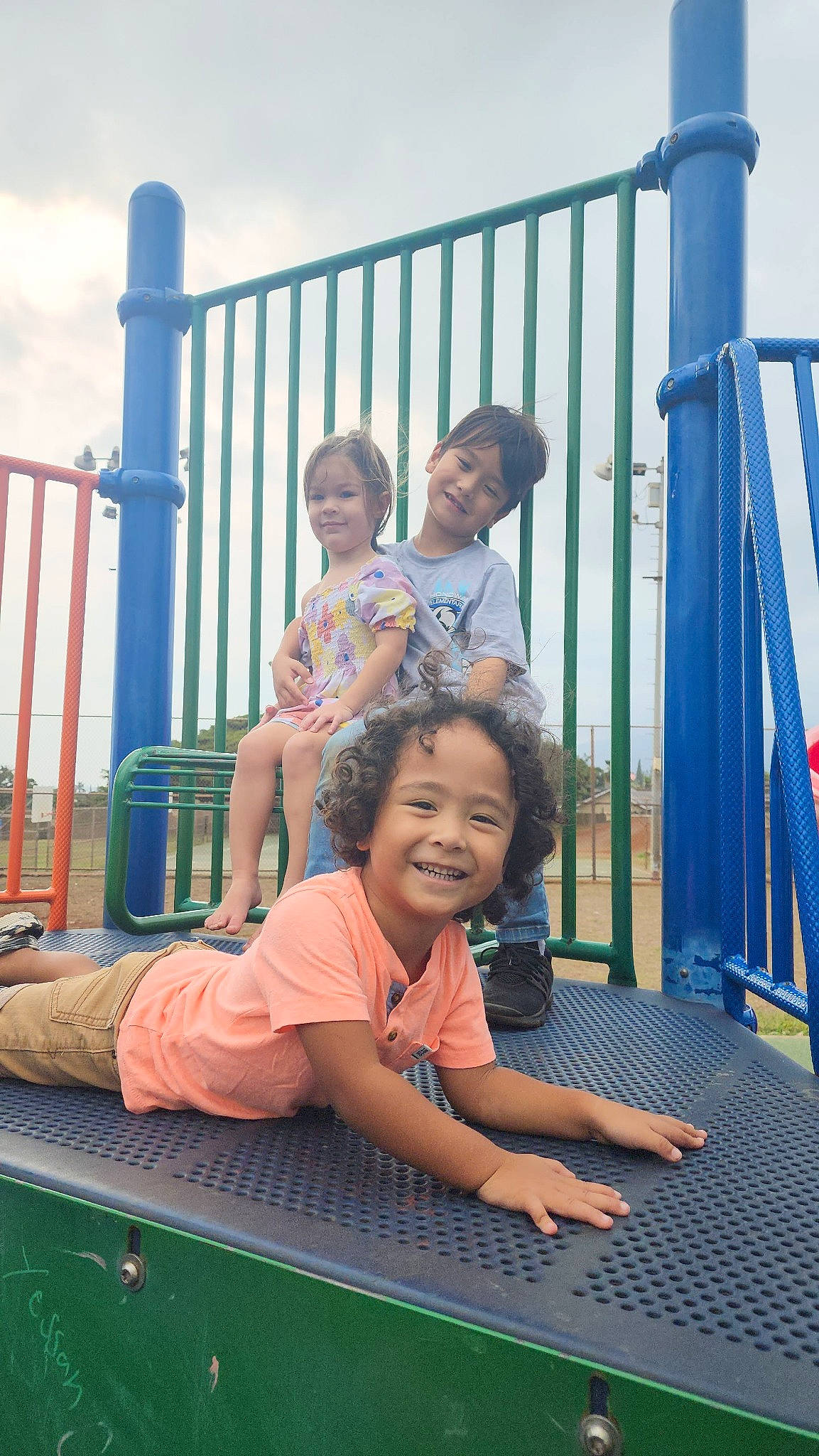 Blue is registered to the contest to win money with this photo: blue, child, city, fence, fun, happy, joy, leisure, people, person, product, recreation, shorts, skin, sky, smile, snapshot, standing, summer, t_shirt