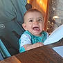 baby, child, high_chair, smiling, happy, indoor, wood, stone_wall, paper, table, clothing, face, person, infant, seat, sunlight, expression, cute, young, cheerful