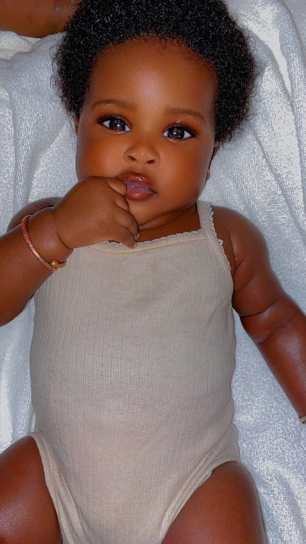 Mané a rejoint le concours — aidez-le/la à gagner de superbes lots ! baby, child, infant, curly_hair, onesie, bracelet, hand, face, skin, lying_down, white_blanket, cute, adorable, portrait, close_up, expression, person, young_child, sleepwear, indoor