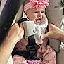 baby, infant, car_seat, pink_flower, headband, hands, safety_harness, smiling, tongue_out, cute, clothing, patterned_pants, white_bib, pacifier, seatbelt, child, indoor, person, happy, close_up