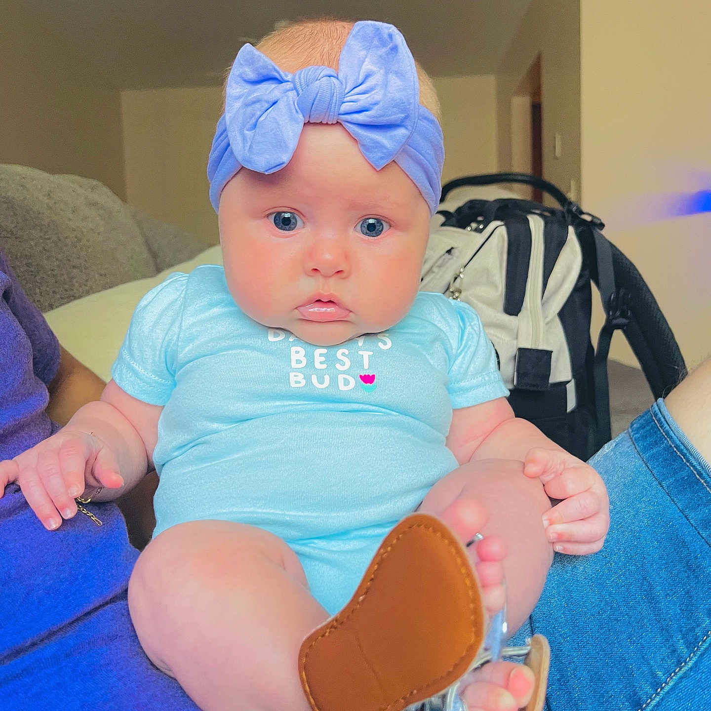 Noelymar joined the competition — help win amazing prizes! adult, baby, blue_eyes, bow, child, clothing, curious, cute, face, footwear, furniture, headband, indoor, infant, lap, onesie, person, shoe, sitting, skin