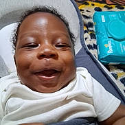 Jayce is registered to the contest to win money with this photo: baby, smiling, infant, white_clothing, baby_seat, pampers, baby_wipes, hand, blanket, pattern, happy, face, closeup, indoor, child, cute, skin, head, comfort, lying_down