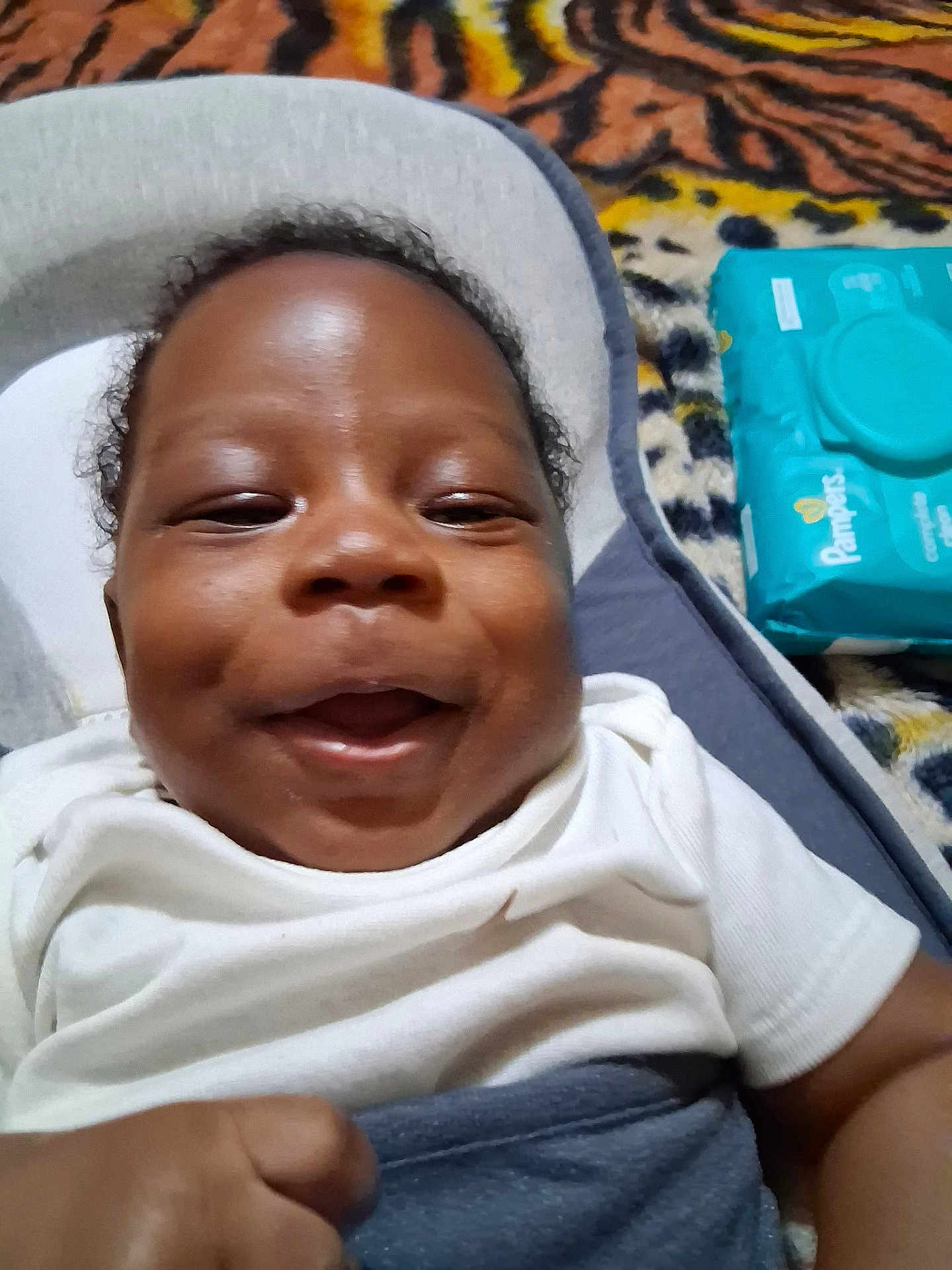 Jayce is registered to the contest to win money with this photo: baby, smiling, infant, white_clothing, baby_seat, pampers, baby_wipes, hand, blanket, pattern, happy, face, closeup, indoor, child, cute, skin, head, comfort, lying_down