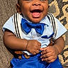 baby, child, smiling, blue_bow_tie, suspenders, blue_pants, light_blue_shirt, couch, cushion, happy, indoor, portrait, cute, person, infant, fashion, seated, hands, face, joy