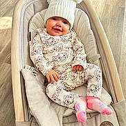 Viviana joined the competition — help win amazing prizes! baby, baby_seat, child, clothing, comfort, cozy, cute, happy, hat, indoor, infant, pajamas, person, pink_socks, pom_poms, portrait, relaxed, seat, smiling, wooden_floor
