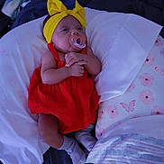 Zariyah joined the competition — help win amazing prizes! baby, bed, blanket, child, comfort, cute, floral_pattern, headband, indoors, infant, lying_down, newborn, pacifier, pillow, red_dress, resting, sleepwear, socks, soft_lighting, yellow_bow