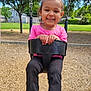 Noella is registered to the contest to win money with this photo: child, toddler, swing, playground, outdoor, smiling, happy, pink_shirt, black_pants, grass, trees, house, daylight, park, fun, play, young, person, nature, recreation