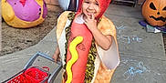 Noella is registered to the contest to win money with this photo: child, costume, hot_dog, shopping_cart, outdoor, halloween, pumpkin, pirate_duck, sidewalk, chalk_drawing, smiling, cute, playful, toy, festive, holiday, person, fun, colorful, celebration