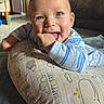 Leo is registered to the contest to win money with this photo: baby, child, smiling, blue_eyes, cushion, pillow, hand, thumb, clothing, striped, indoor, floor, happy, face, person, cute, baby_bed, home, soft, toddler