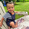 toddler, child, smiling, outdoor, grass, chair, cushion, striped_shirt, overalls, basketball_hoop, rocking_horse, greenery, tree, sunlight, playground, happy, portrait, barefoot, summer, daylight