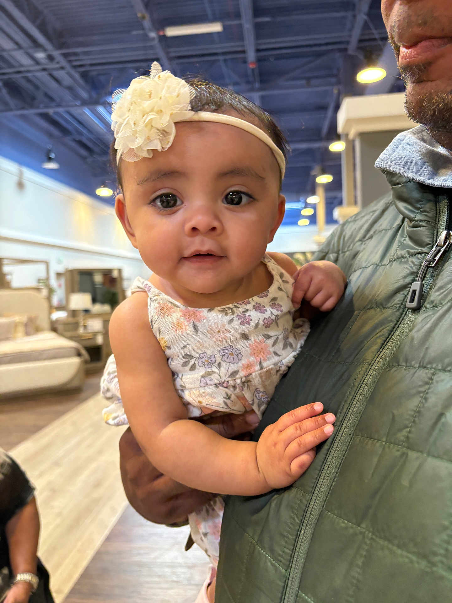 Ava Rose joined the competition — help win amazing prizes! baby, child, infant, person, adult, hand, face, headband, flower, dress, indoor, furniture, bed, lamp, floor, jacket, holding, curious, portrait, shopping