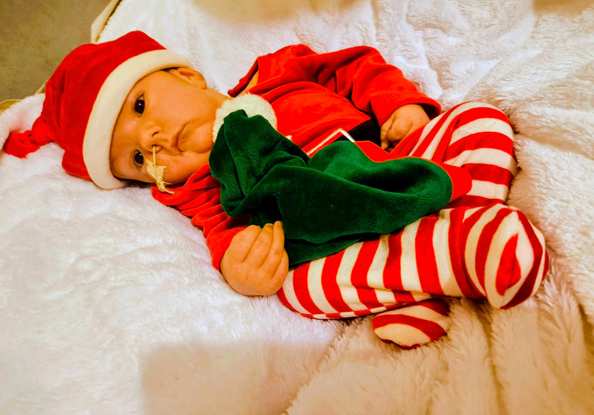 Timeo a rejoint le concours — aidez-le/la à gagner de superbes lots ! baby, infant, santa_hat, santa_costume, striped_pajamas, christmas, holiday, blanket, cozy, plush, lying_down, portrait, face, eyes, hand, skin, soft_texture, red_clothing, white_fur, nap_time