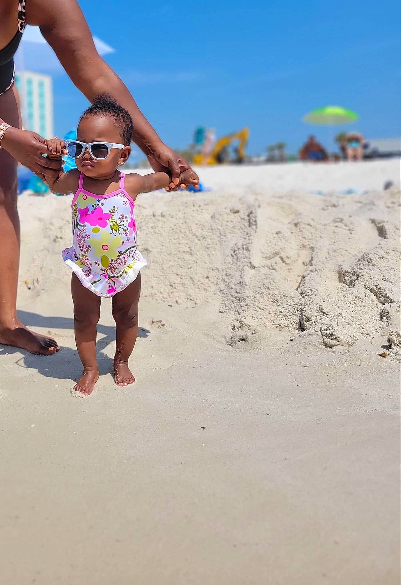 River is registered to the contest to win money with this photo: barefoot, beach, eyewear, foot, fun, gesture, goggles, happy, leisure, people_in_nature, people_on_beach, person, sand, shorts, sky, summer, sunglasses, swimwear, thigh, toddler