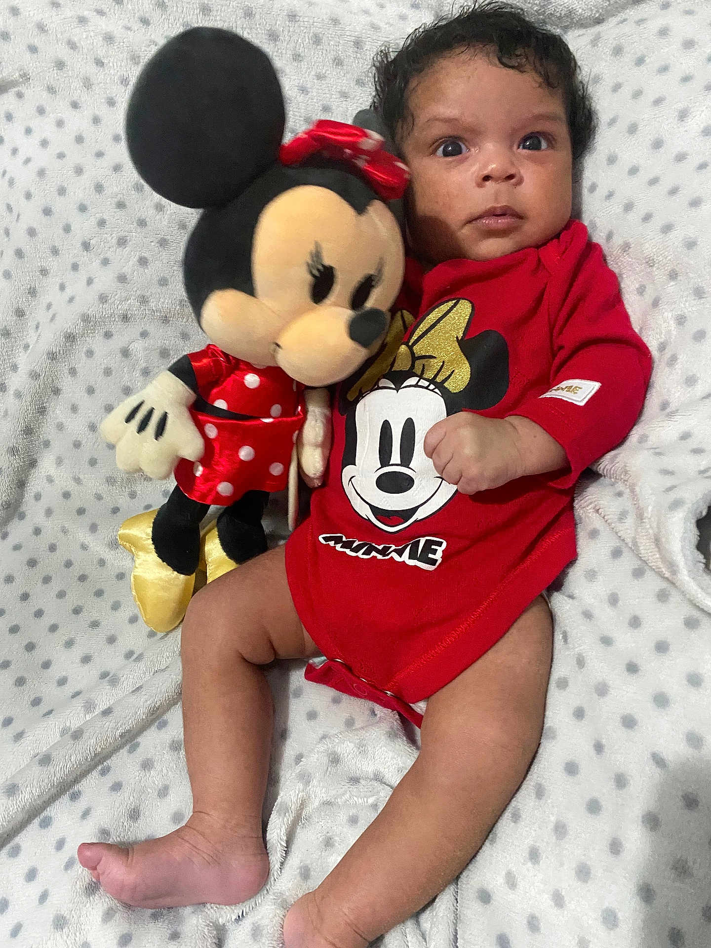 Layla joined the competition — help win amazing prizes! baby, infant, plush_toy, minnie_mouse, red_clothing, blanket, polka_dots, cute, child, soft_texture, lying_down, toy, smiling_face, indoors, portrait, young_child, human, toddler, sleepwear, cuddly