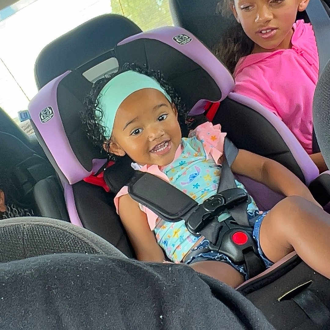 Namari is registered to the contest to win money with this photo: backseat, car, car_seat, child, clothing, family, girl, hair, happy, headband, interior, person, safety, seat, seatbelt, smile, sunlight, toddler, transportation, window