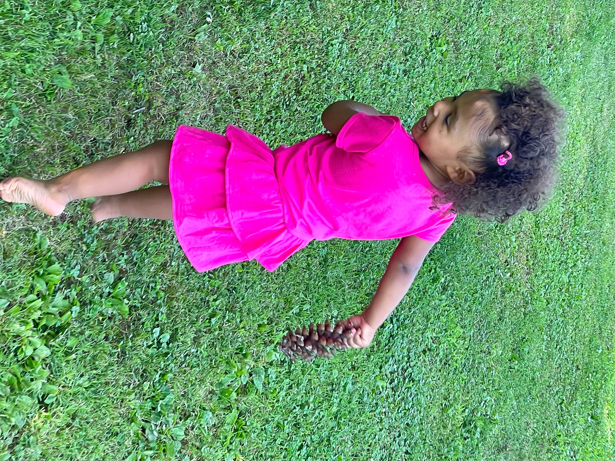 Kinsley is registered to the contest to win money with this photo: baby_toddler_clothing, fun, garden, grass, grass_family, grassland, green, groundcover, happy, human_leg, lawn, leisure, magenta, meadow, pattern, people_in_nature, person, plant, shrub, t_shirt