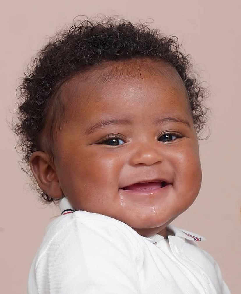 Jacob is registered to the contest to win money with this photo: baby, infant, smiling, curly_hair, face, drool, white_clothing, portrait, closeup, happy, child, cute, skin, eyes, mouth, head, young, background, studio, person