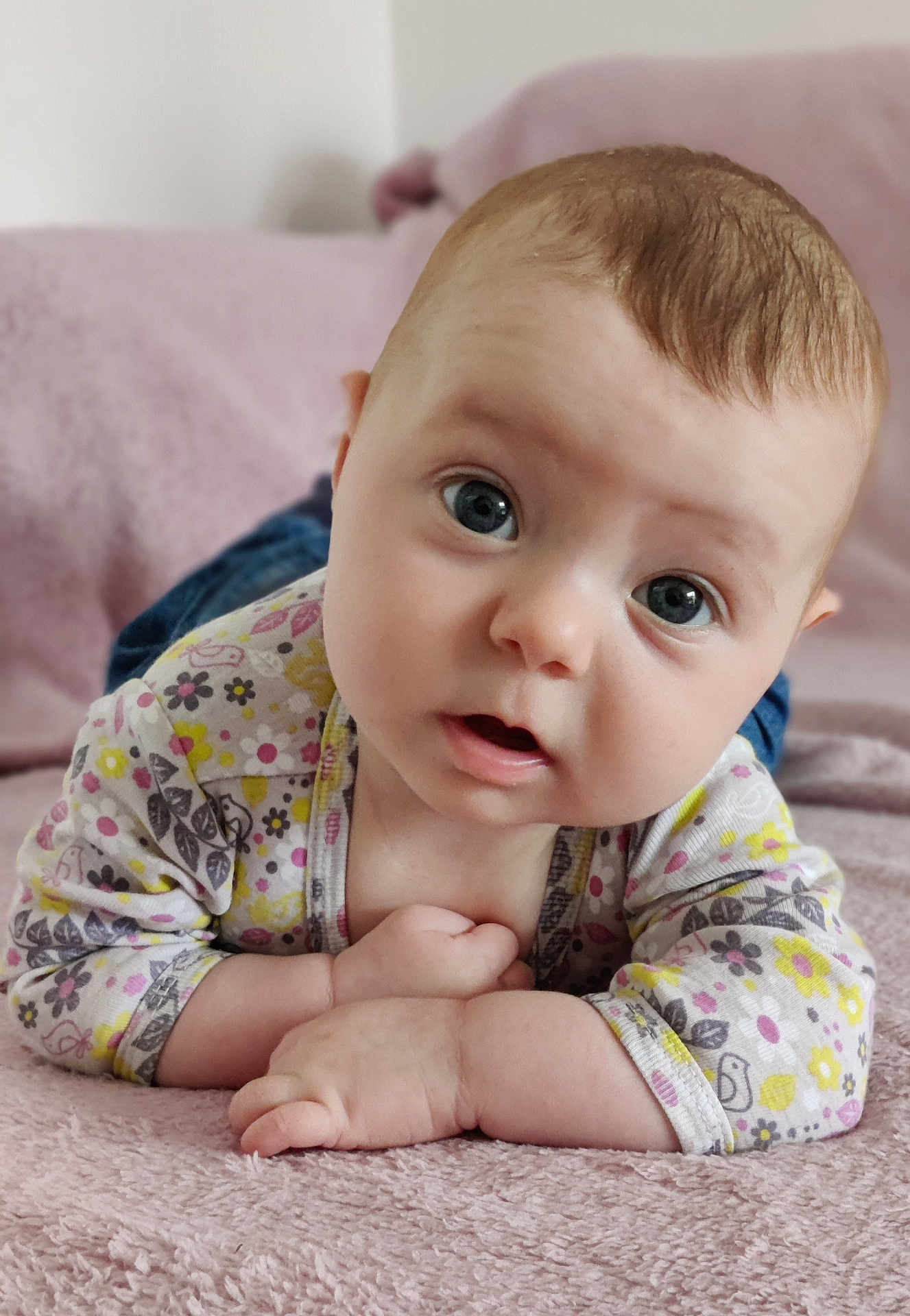 Enora a rejoint le concours — aidez-le/la à gagner de superbes lots ! baby, infant, child, face, eyes, hands, blanket, bed, clothing, patterned_clothes, skin, head, expression, cute, indoors, soft_texture, portrait, lying_down, pink, curious