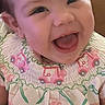 baby, child, infant, smiling, laughing, portrait, face, indoor, close_up, happy, joyful, sitting, clothing, dress, patterned_outfit, floral, vehicles, pink, brown_hair, photography