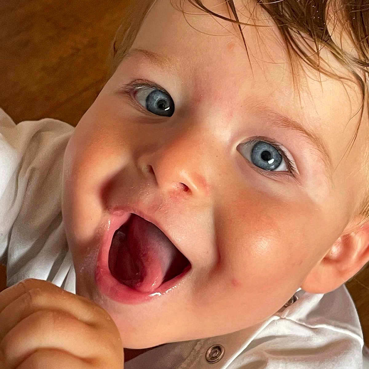 Elino a rejoint le concours — aidez-le/la à gagner de superbes lots ! blue_eyes, button, child, close_up, cute, emotion, expression, face, hair, hand, happy, indoors, joy, mouth_open, natural_light, portrait, skin, smiling, toddler, white_clothing
