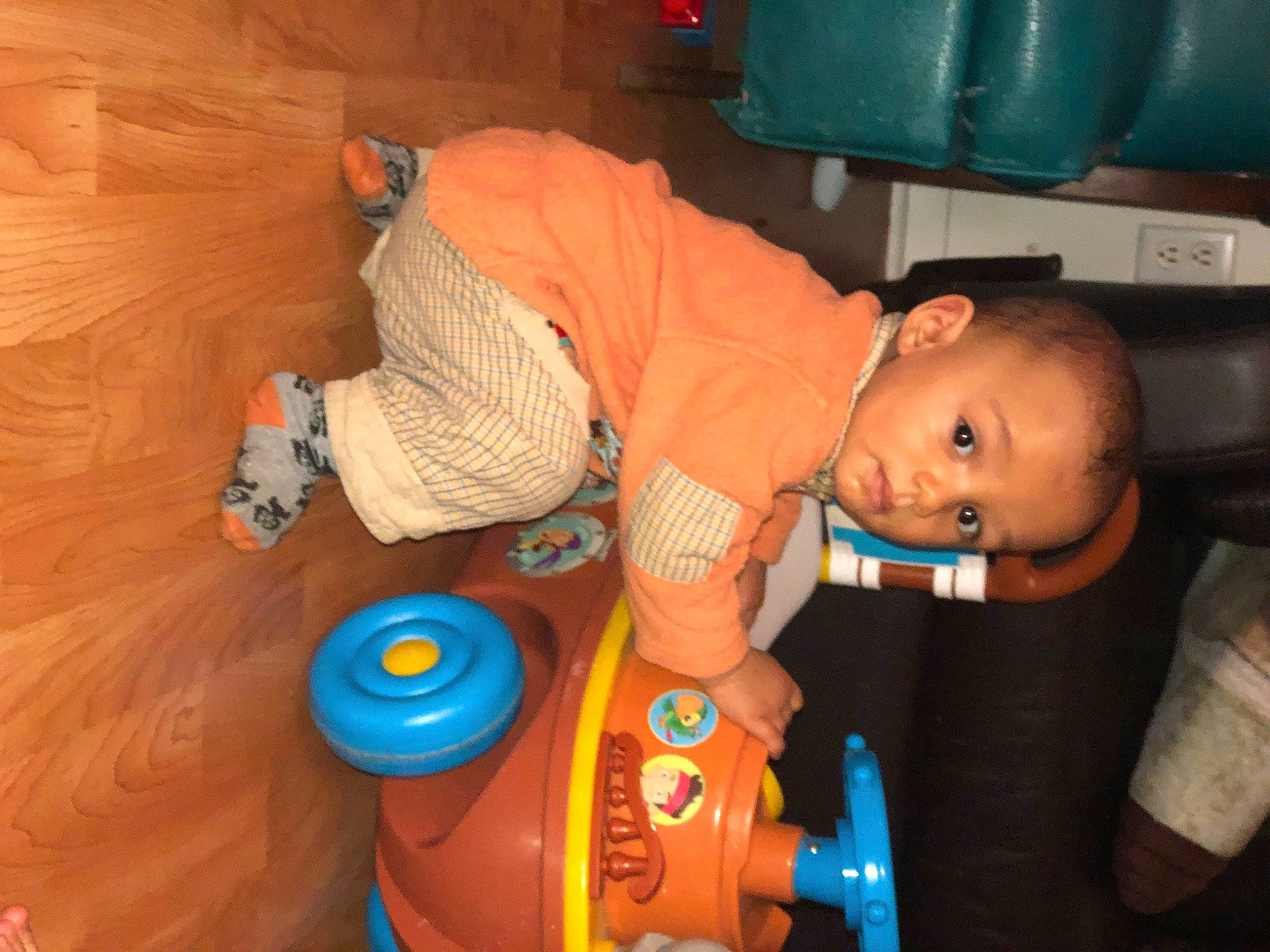 Jahyan a rejoint le concours — aidez-le/la à gagner de superbes lots ! baby, baby_products, baby_toys, child, electric_blue, flooring, fun, hardwood, orange, organ, person, plastic, plastic_bottle, play, room, sitting, smile, toddler, toy, vehicle_door