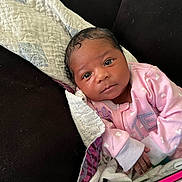 Rayn is registered to the contest to win money with this photo: baby, blanket, couch, cozy, curious, eyes, face, hand, heart_pattern, indoor, infant, newborn, person, phone, pink_clothing, portrait, quilt, resting, skin, soft_lighting