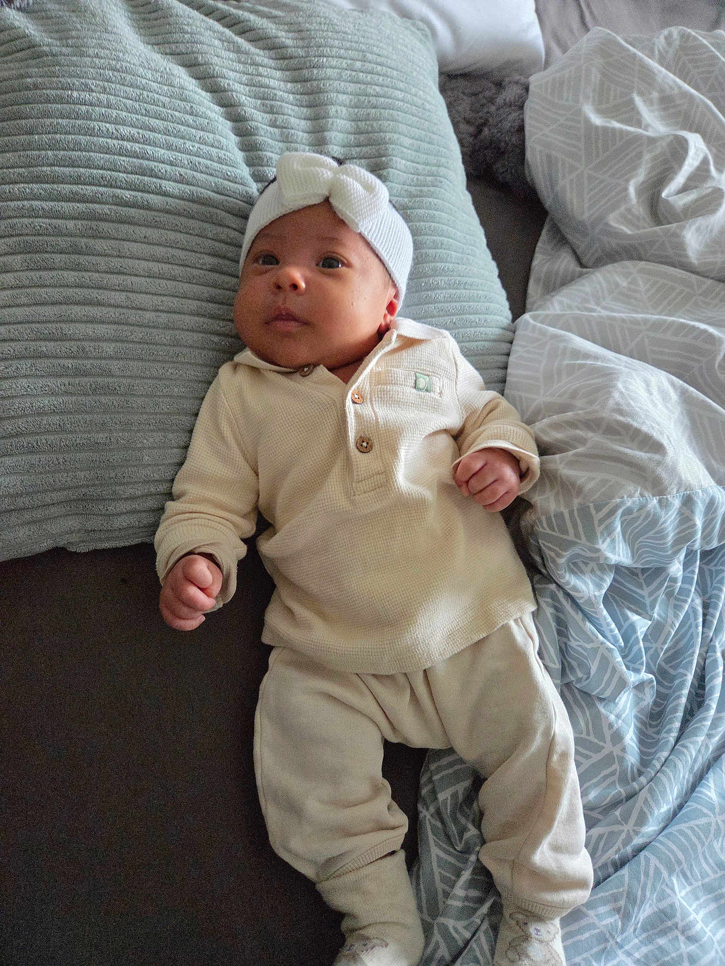 Thays participe au concours pour gagner de l'argent avec cette photo : baby, infant, headband, bow, white_clothing, pillow, blanket, bed, sleepwear, socks, cute, lying_down, indoors, soft_texture, child, small_hands, expression, comfort, resting, young