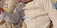Wyatt is registered to the contest to win money with this photo: baby, feeding, spoon, pajamas, cushion, baby_seat, child, infant, face, hand, blanket, white_clothing, blue_eyes, indoor, closeup, person, food, comfort, soft, care