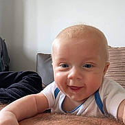 Wyatt is registered to the contest to win money with this photo: baby, infant, child, smiling, drool, face, skin, hand, arm, hair, couch, pillow, white_shirt, blue_trim, indoor, closeup, person, happy, cute, portrait