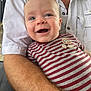 baby, child, smiling, striped_shirt, adult_arm, white_shirt, portrait, close_up, happy, person, human, skin, face, eyes, mouth, holding, casual_clothing, indoor, expression, cute