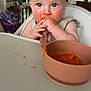 baby, blue_eyes, high_chair, orange_food, spoon, messy_face, feeding_time, indoor, child, infant, kitchen, table, food, meal, cute, young_child, person, face, hands, bright_light
