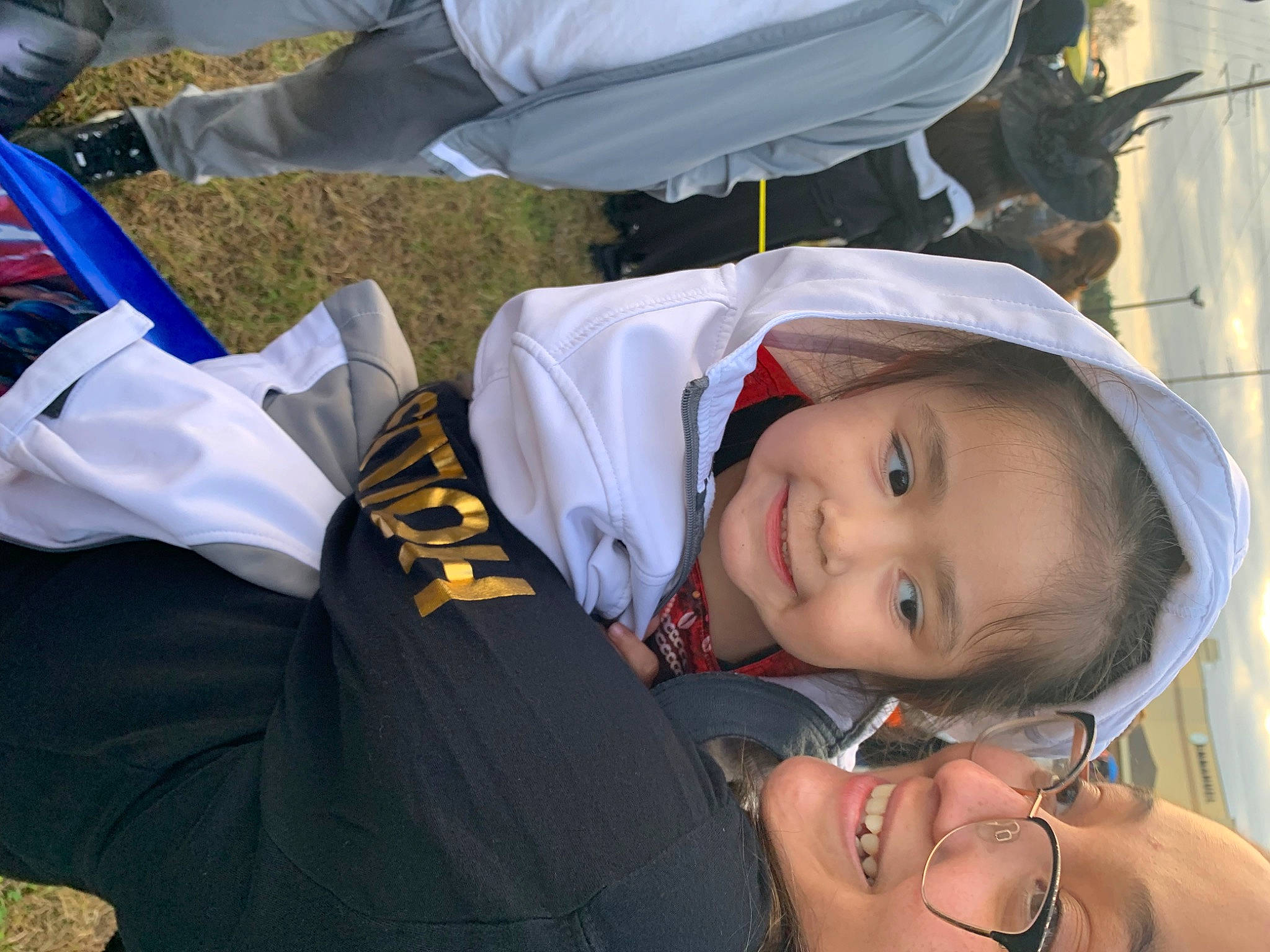 Liliana is registered to the contest to win money with this photo: child, event, fun, gesture, grass, happy, hat, jewellery, joy, laugh, leisure, necklace, person, sitting, smile, social_group, toddler, tradition, tree, uniform