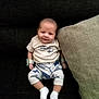 Elmer joined the competition — help win amazing prizes! baby, infant, smile, couch, pillow, white_shirt, patterned_pants, socks, wristbands, indoor, seated, cute, small_person, child, face, head, comfort, relaxation, home, furniture