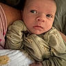 Sutton is registered to the contest to win money with this photo: newborn, baby, infant, child, face, eyes, portrait, close_up, lying_down, pajamas, onesie, clothing, blanket, bed, adult_arm, cozy, indoors, soft_lighting, looking_away, photograph