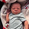 Sutton joined the competition — help win amazing prizes! newborn, baby, infant, child, portrait, face, eyes, hand, onesie, gray_clothing, blanket, plush, lying_down, indoors, close_up, cozy, awake, serious_expression, soft_fabric, photography