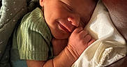 Sutton is registered to the contest to win money with this photo: newborn, baby, sleeping, infant, face, portrait, cozy, blanket, pillow, hand, closed_eyes, peaceful, indoors, couch, green_clothing, soft_lighting, plush_toy, resting, curled_up, family_photo