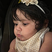 Rut Rodríguez joined the competition — help win amazing prizes! baby, child, headband, flower, curly_hair, closeup, face, expression, bib, infant, skin, portrait, cute, young_child, dark_background, soft_lighting, looking_down, indoor, adorable, focused