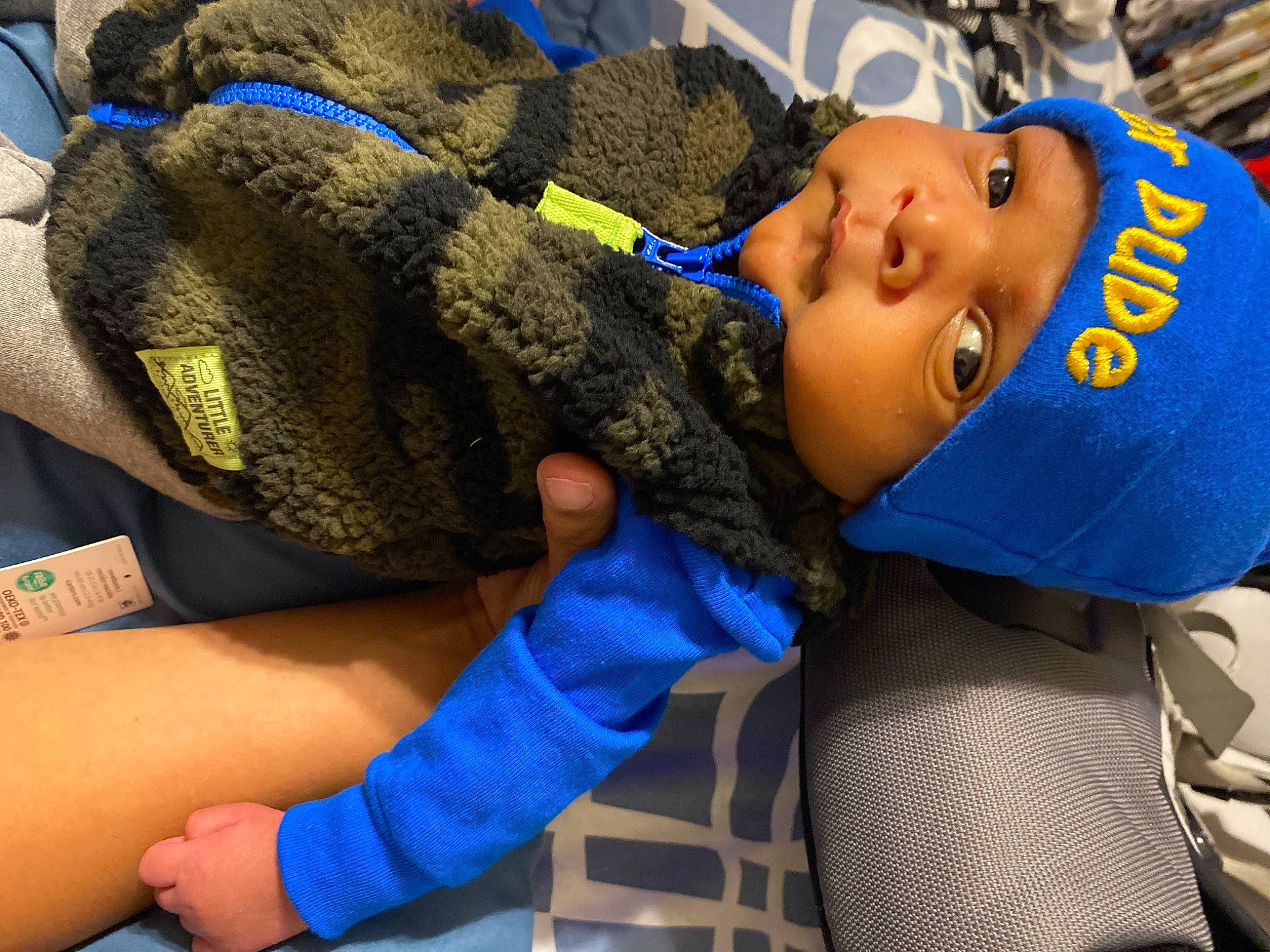 Elijah is registered to the contest to win money with this photo: blue, cap, car_seat, child, comfort, elbow, electric_blue, eye, fashion_accessory, fun, gesture, happy, headwear, leisure, nail, person, personal_protective_equipment, thumb, toddler, travel