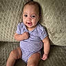 baby, infant, smiling, purple_onesie, polka_dot, couch, textured_fabric, sitting, happy, child, skin, face, arm, leg, furniture, indoor, cute, portrait, young_child, comfortable