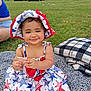 toddler, child, smile, hat, dress, outdoor, grass, blanket, snack, picnic, person, summer, happy, red, white, blue, pattern, footwear, casual, family