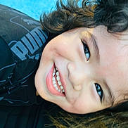 Jayren joined the competition — help win amazing prizes! black_shirt, blue_background, casual_clothing, child, childhood, close_up, curly_hair, cute, expression, face, happy, head, joyful, person, portrait, puma_logo, skin, smile, teeth, young