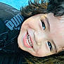 black_shirt, blue_background, casual_clothing, child, childhood, close_up, curly_hair, cute, expression, face, happy, head, joyful, person, portrait, puma_logo, skin, smile, teeth, young