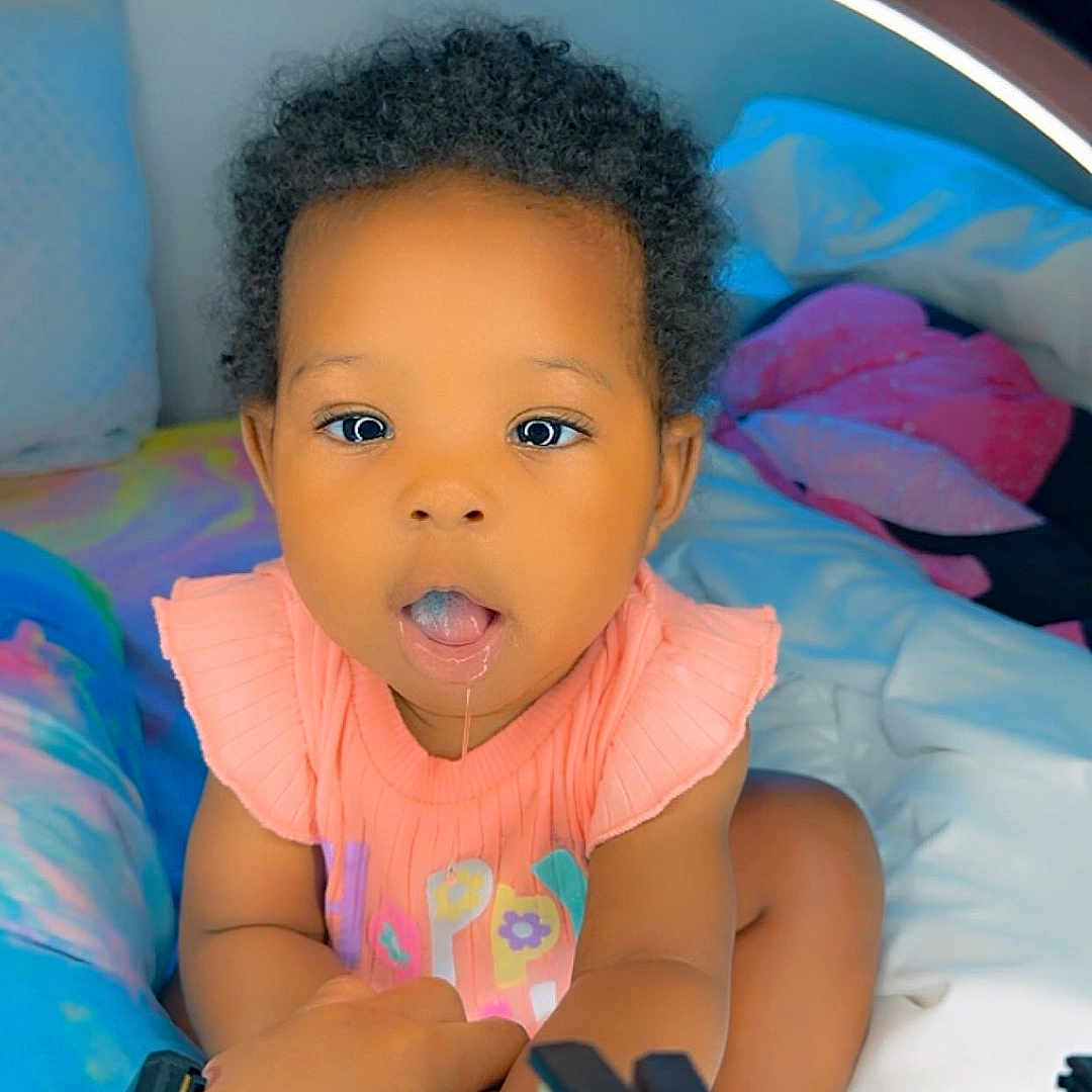 Miley is registered to the contest to win money with this photo: baby, bed, bedroom, clothing, crib, cushion, face, furniture, gun, happy, head, homedecor, indoors, infantbed, person, photography, portrait, smile, t_shirt, weapon