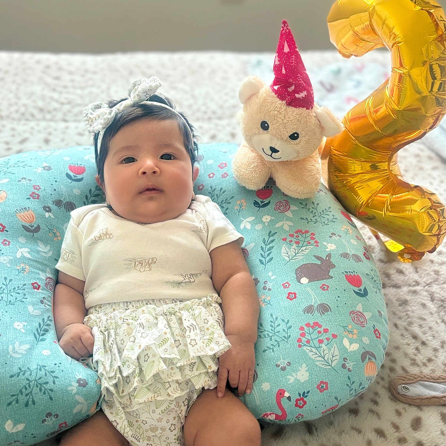 Ashely is registered to the contest to win money with this photo: baby, balloon, bed, celebration, child, chubby_cheeks, comfortable, cushion, cute, decor, floral_pattern, headband, indoors, infant, lying_down, number_two, patterned_fabric, plush_toy, ruffled_clothing, soft_toy