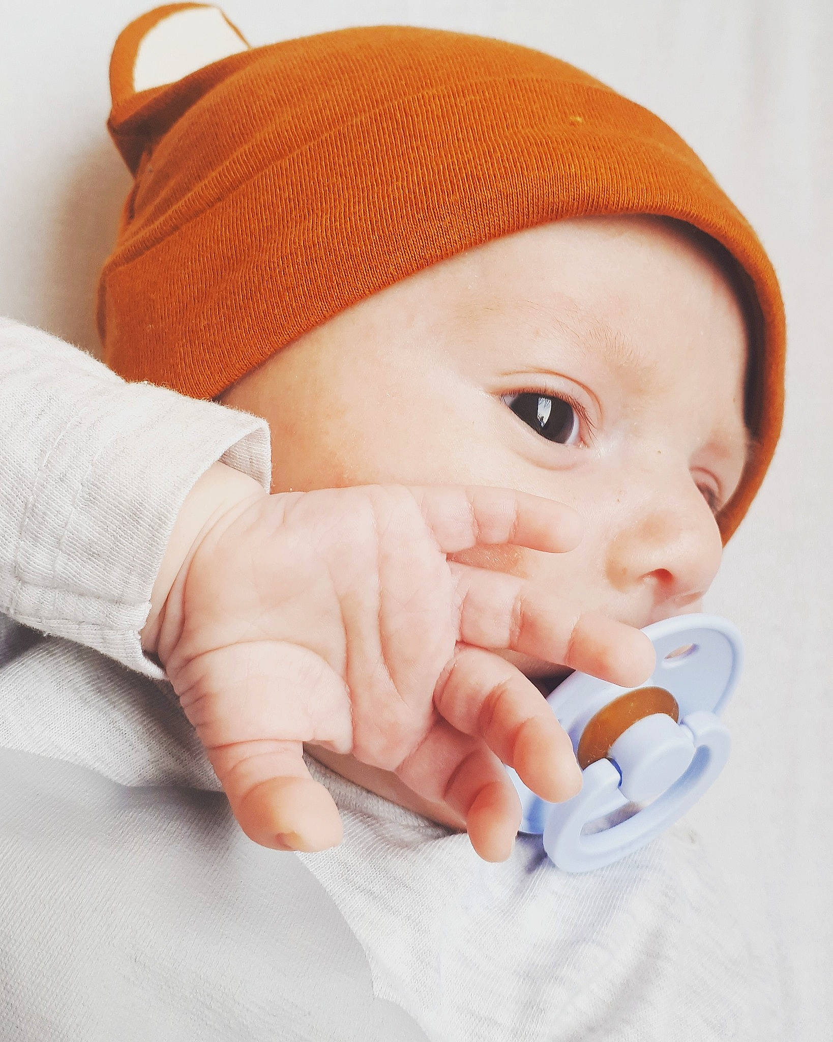 Noé participe au concours pour gagner de l'argent avec cette photo : baby, beanie, cap, cheek, child, face, finger, forehead, gesture, hand, head, headgear, lip, mouth, nose, orange, person, product, skin, thumb