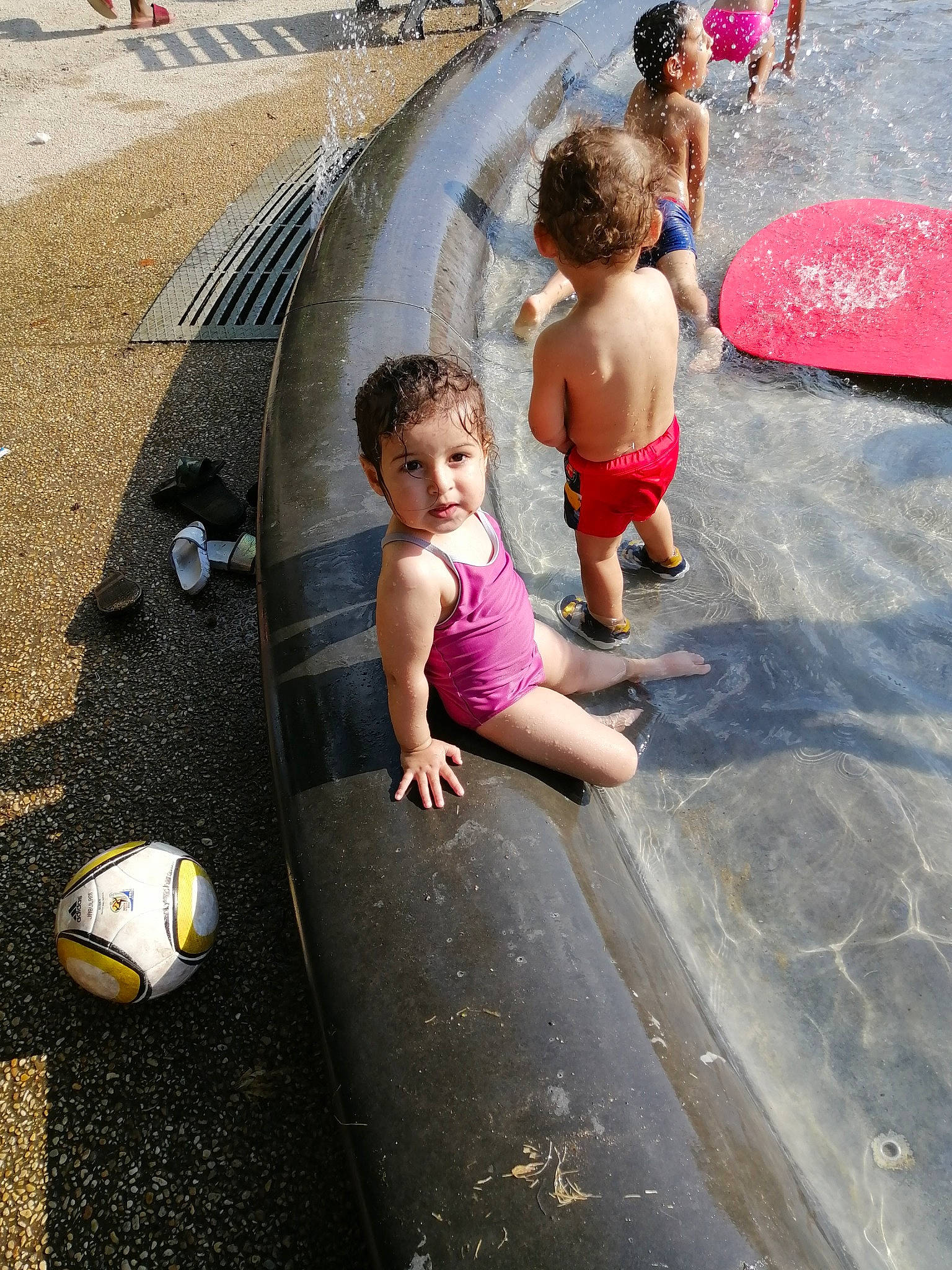 Nelya participe au concours pour gagner de l'argent avec cette photo : child, concrete, fountain, fun, leg, leisure, people, person, pink, play, public_space, recreation, road_surface, sidewalk, street, summer, toddler, vacation, water, water_feature