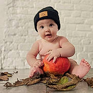 Matías a rejoint le concours — aidez-le/la à gagner de superbes lots ! baby, bare_chest, beanie, brick_wall, child, curious_expression, cute, dry_leaves, fall, floor, hands, hat, indoor, orange, plant, portrait, pumpkin, seasonal, sitting, toes