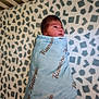 newborn, baby, blanket, crib, infant, wrapped, sleeping, soft_texture, patterned_bedding, cute, portrait, indoors, child, peaceful, cozy, fabric, resting, head, face, baby_bedding