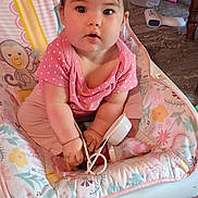 Harper is registered to the contest to win money with this photo: baby, child, infant, pink_clothing, baby_chair, floral_pattern, indoor, cute, curious, face, human, seat, toy, person, sitting, young_child, plush, home_interior, floor, furniture